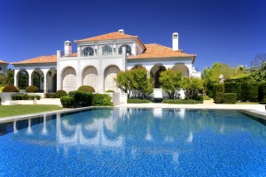 A large pool with a nice house in the background.
